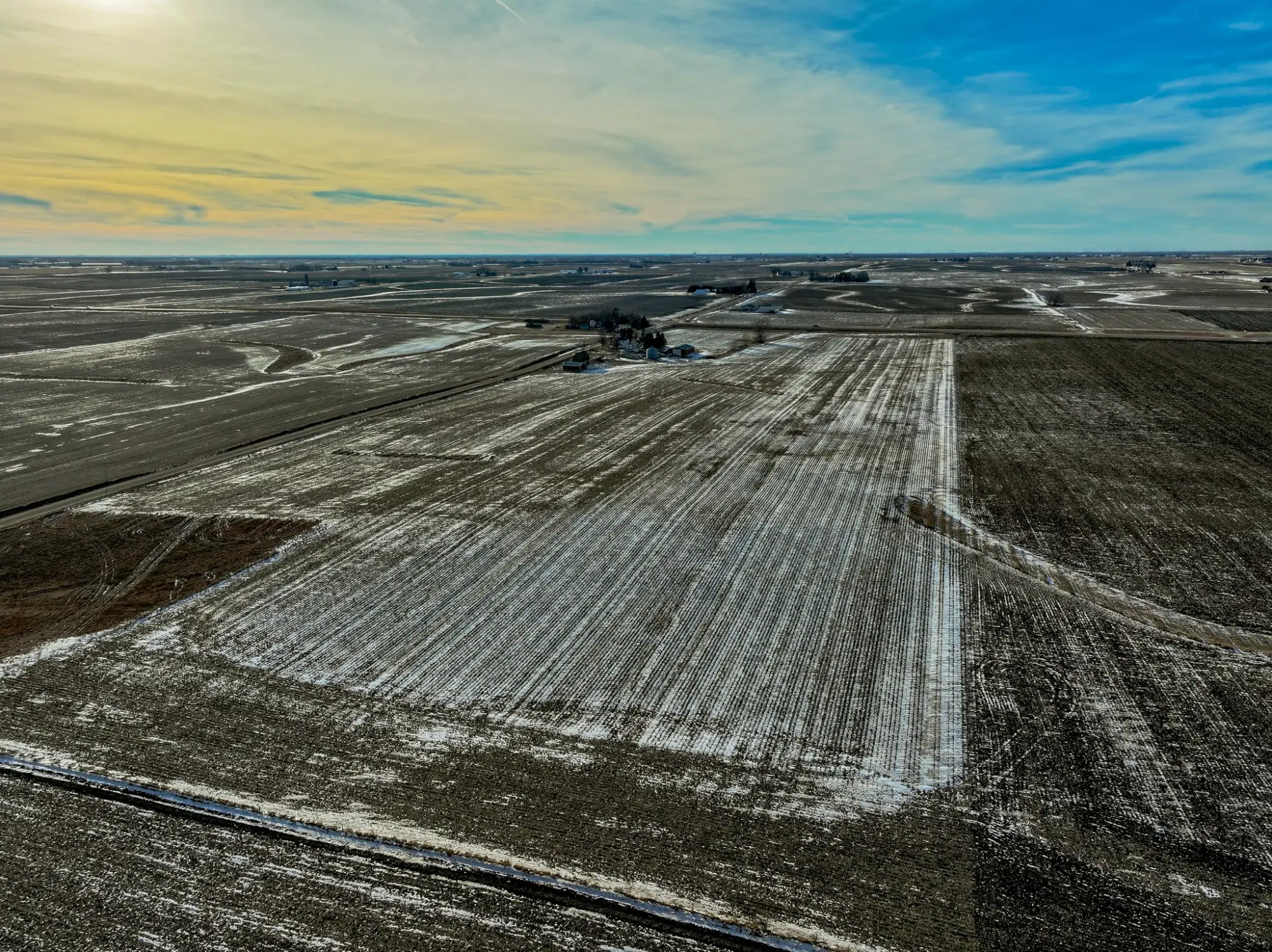 Iowa farmland. The sky is bright blue with a hint of orange with a few clouds.